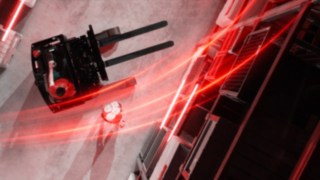 Der Linde MH-Schubmaststapler Ri16 aus der Vogelperspektive mit roten Lichtspuren, daneben eine Person, die einen Handstand macht.